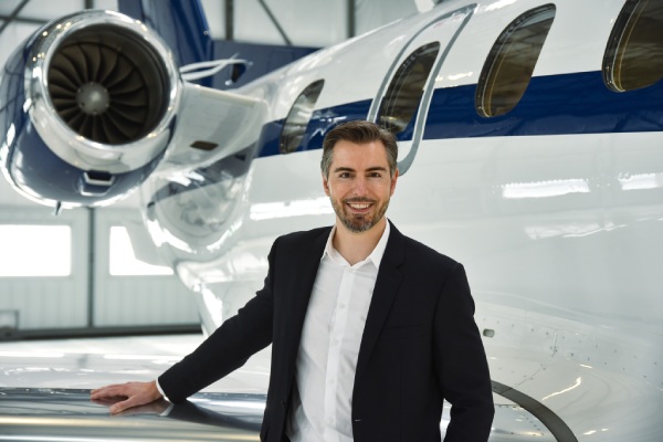 Gentleman standing in front of a private jet in the hanger.
