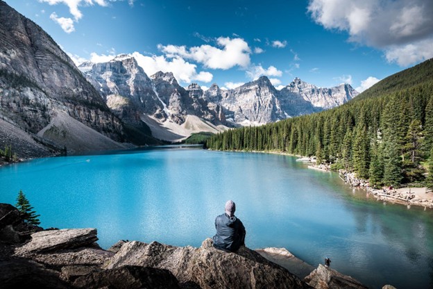 Person sitting on a rock viewing the Canadian Rocky Mountains in Banff, Alberta
