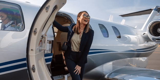 A confident woman in chic travel attire stepping down from a private aircraft.