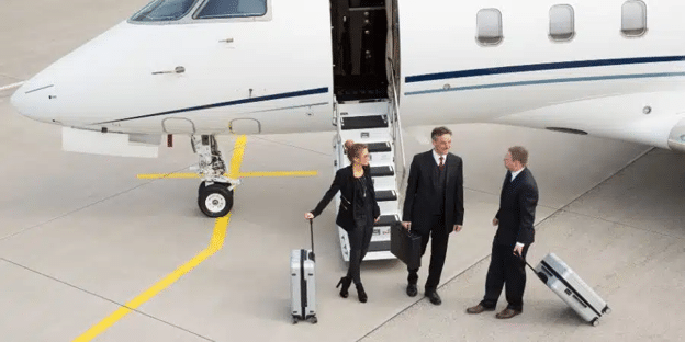 Business executives departing a private jet on the tarmac, carrying luggage .