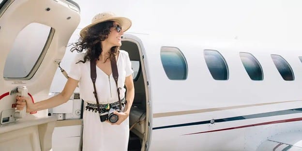 Woman carrying a camera disembarking a luxury private airplane during a holiday trip.